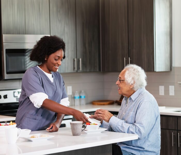 care giver making breakfast for a seniors