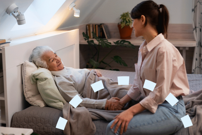 Elderly woman with dementia resting in bed while her caregiver holds her hand.
