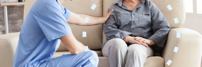 Nurse offering comfort to an elderly dementia patient sitting on a couch.