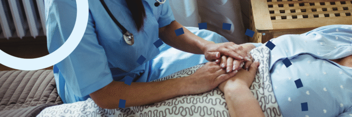 Hospice nurse holding hands with a dementia patient in bed.