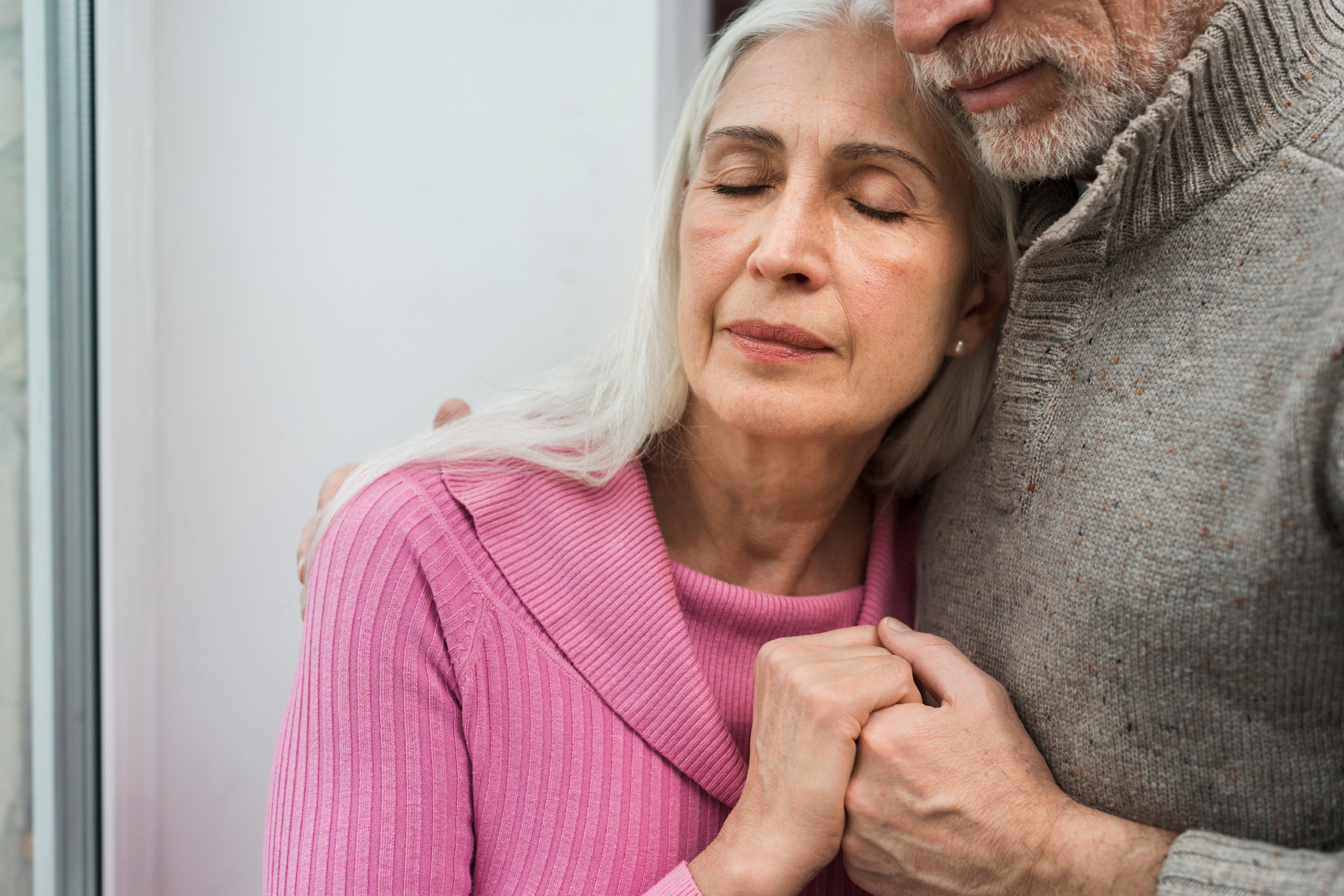 A senior couple is embracing one another.