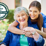 Caregiver and senior are happily embracing.