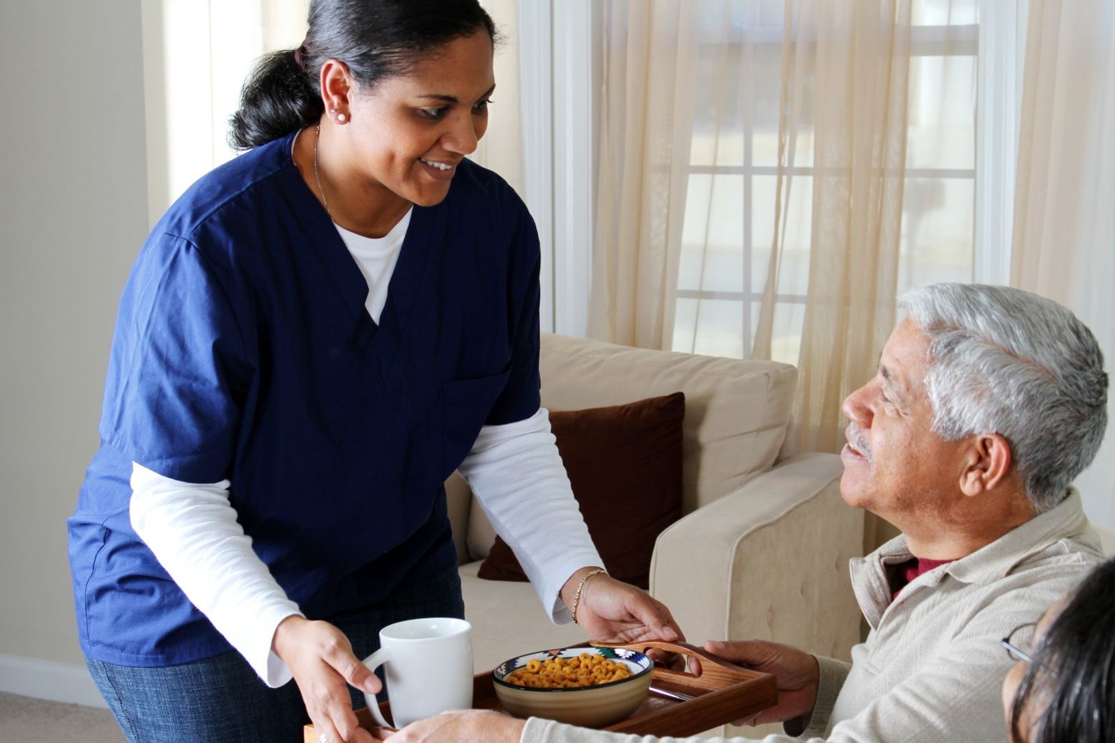 Woman caregiver providing personal care support for senior man at home
